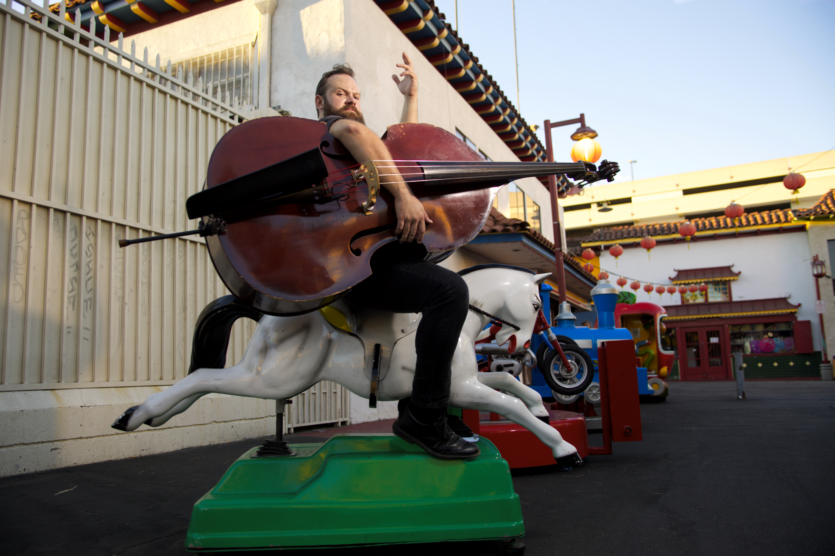 Bass legend Chris Rolontz riding a children's toy machine pony in a parking lot.